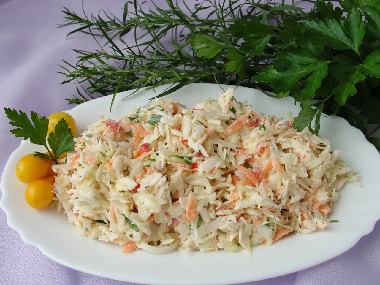 Pyszna surówka z białej kapusty z marchewką i papryką, ozdobiona pomidorkami i zieleniną. Idealna inspiracja, co zrobić z białej kapusty!