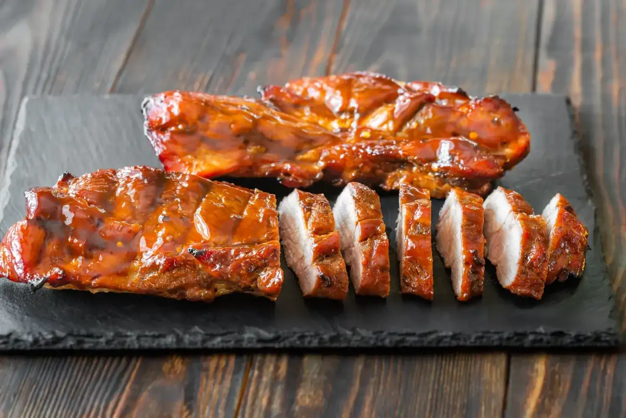 Soczyste, glazurowane żeberka wieprzowe, pokrojone na kawałki. Idealne do grillowania, zastanawiasz się, jak długo wędzić polędwiczki wieprzowe, by osiągnąć taki efekt?