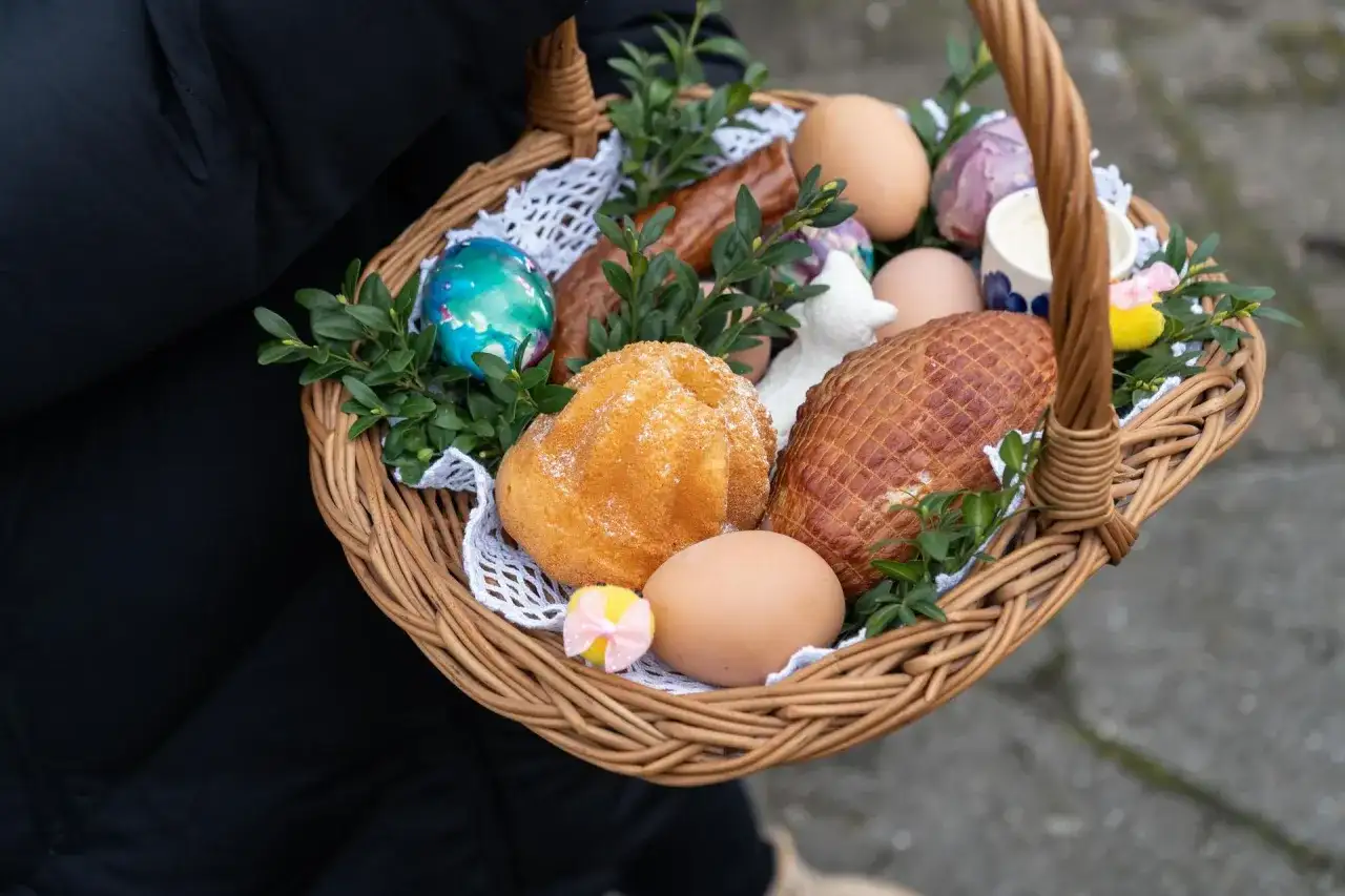 Wielkanocny koszyczek z jajkami, babką, kiełbasą i wędliną.