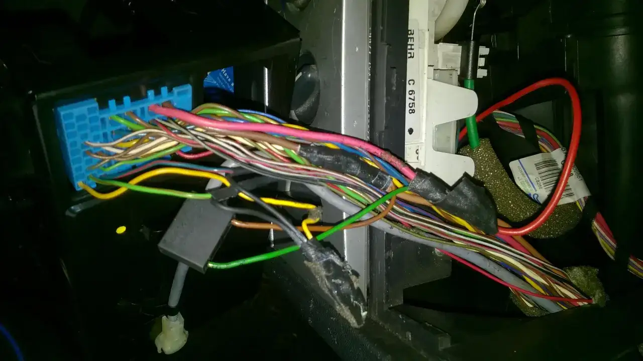 Plątanina przewodów w Opel Meriva, widoczny niebieski konektor i fragmenty instalacji elektrycznej, być może związane z lokalizacją bezpieczników.