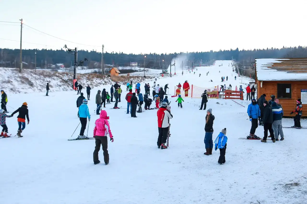 Stok narciarski w Bodzentynie tętni życiem. Widok z kamery online pokazuje narciarzy i snowboardzistów szusujących po ośnieżonych stokach.