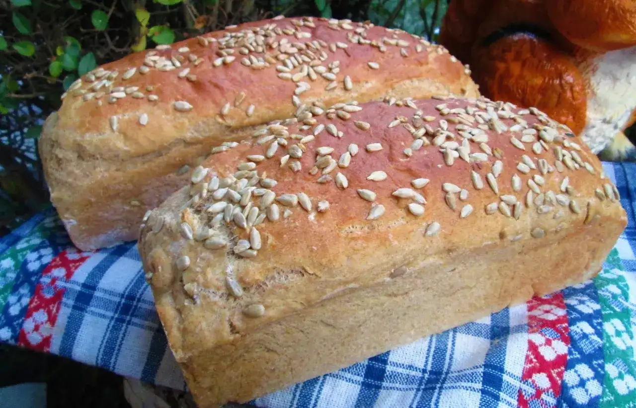 Dwa bochenki domowego chleba posypane słonecznikiem, idealne do nauki jak upiec chleb w domu.