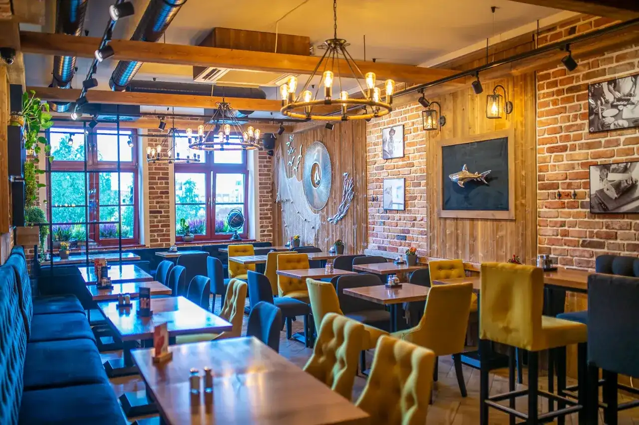 Przytulne wnętrze z ceglanymi ścianami i drewnianymi elementami, idealne na odkrycie najlepszych restauracji w Sopocie.