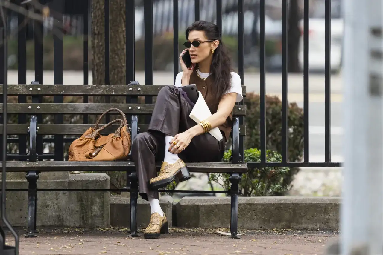 Kobieta w brązowych mokasynach i białych skarpetkach siedzi na ławce.