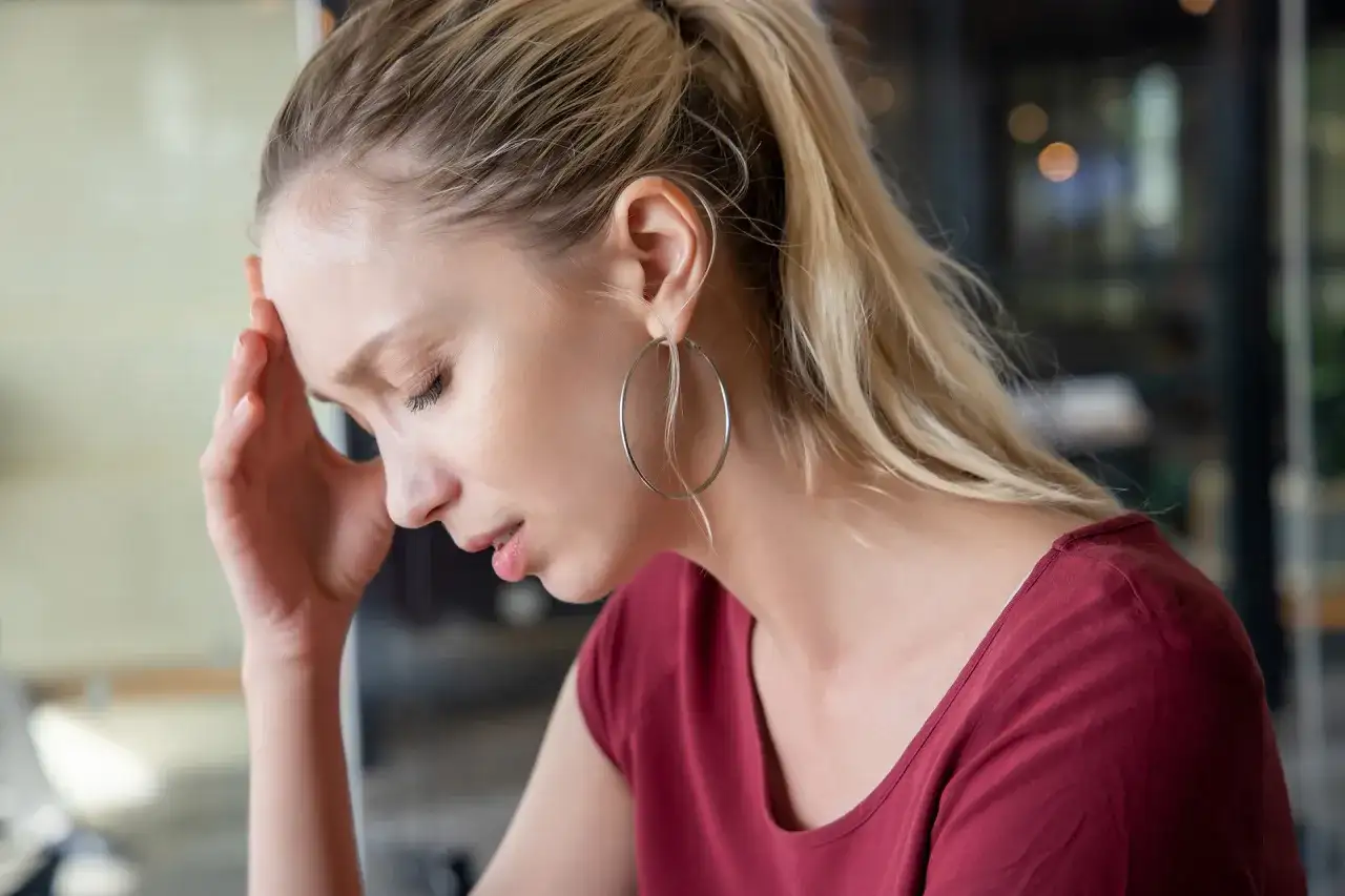 Kobieta z dłonią na czole, cierpiąca na zawroty głowy od kręgosłupa szyjnego.