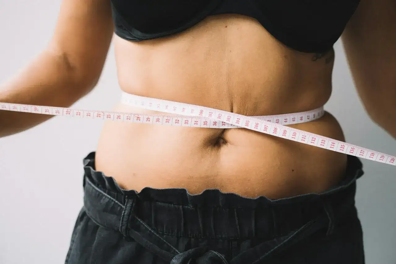 Kobieta mierzy talię centymetrem. Czy to początek drogi, jak szybko schudnąć 20 kg?