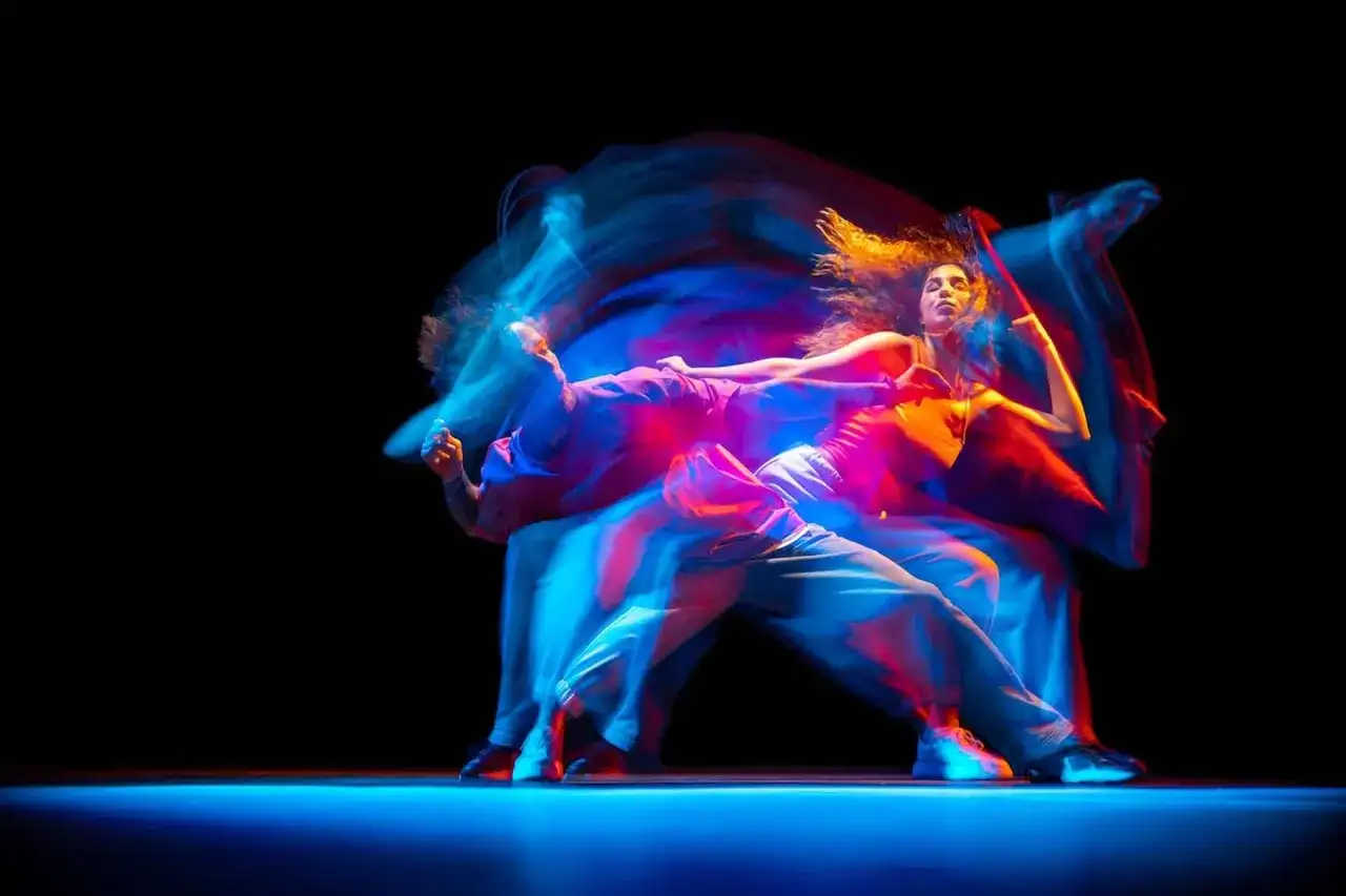 Tancerze w ruchu, tworzący świetlne smugi. Zastanawiasz się, ile zarabia choreograf tańca?