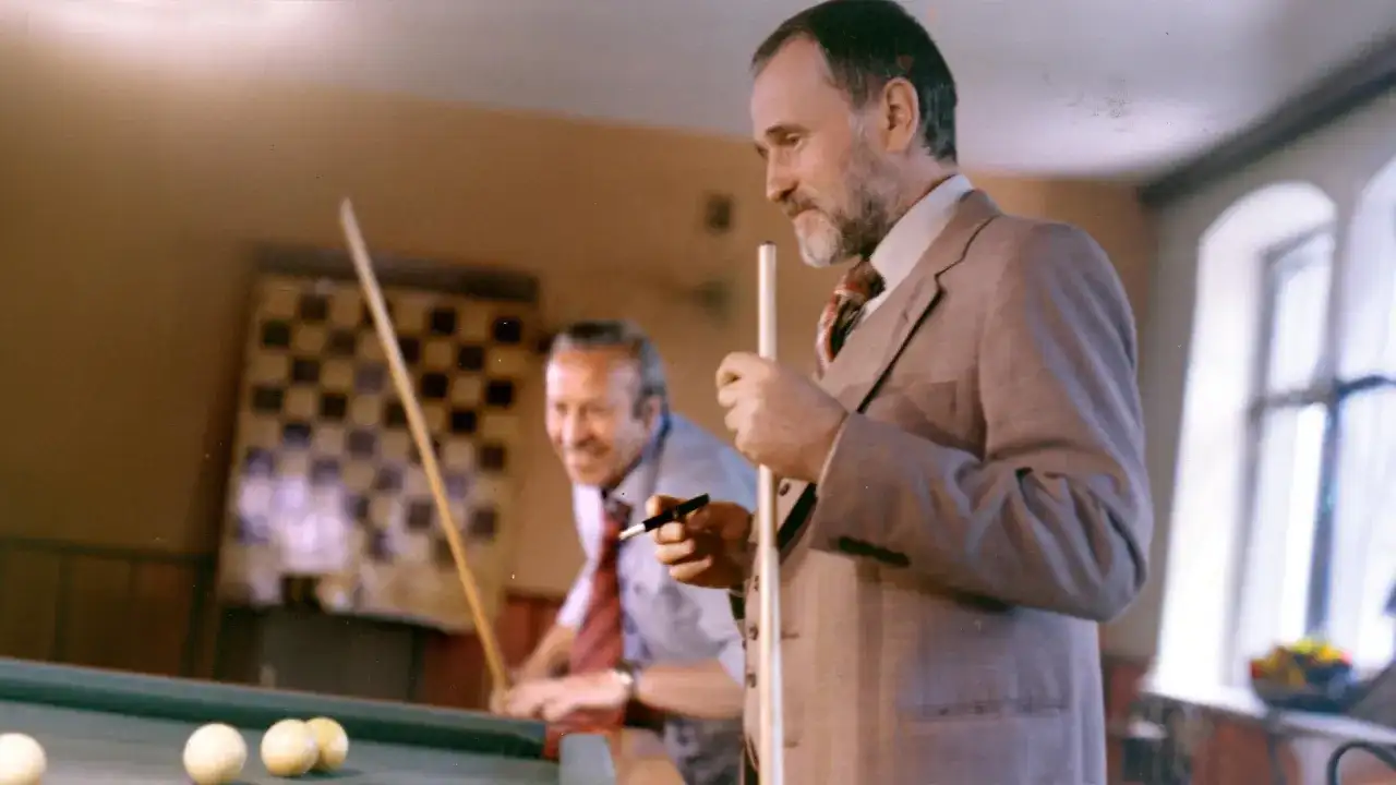 Dwóch mężczyzn gra w bilard. Scena przypomina miejsce, gdzie kręcono "Wielkiego SzU".