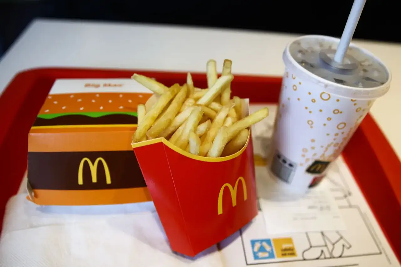 Duże frytki w czerwonym opakowaniu McDonald's obok pudełka Big Mac i napoju.