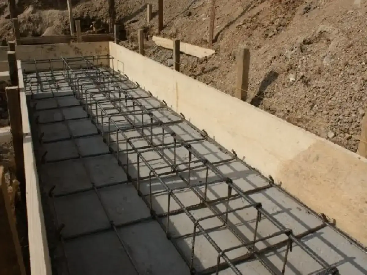 Siatka zbrojeniowa w deskowaniu fundamentu. Widać regularny układ, co ile strzemiona na fundament, gotowe do zalania betonem.