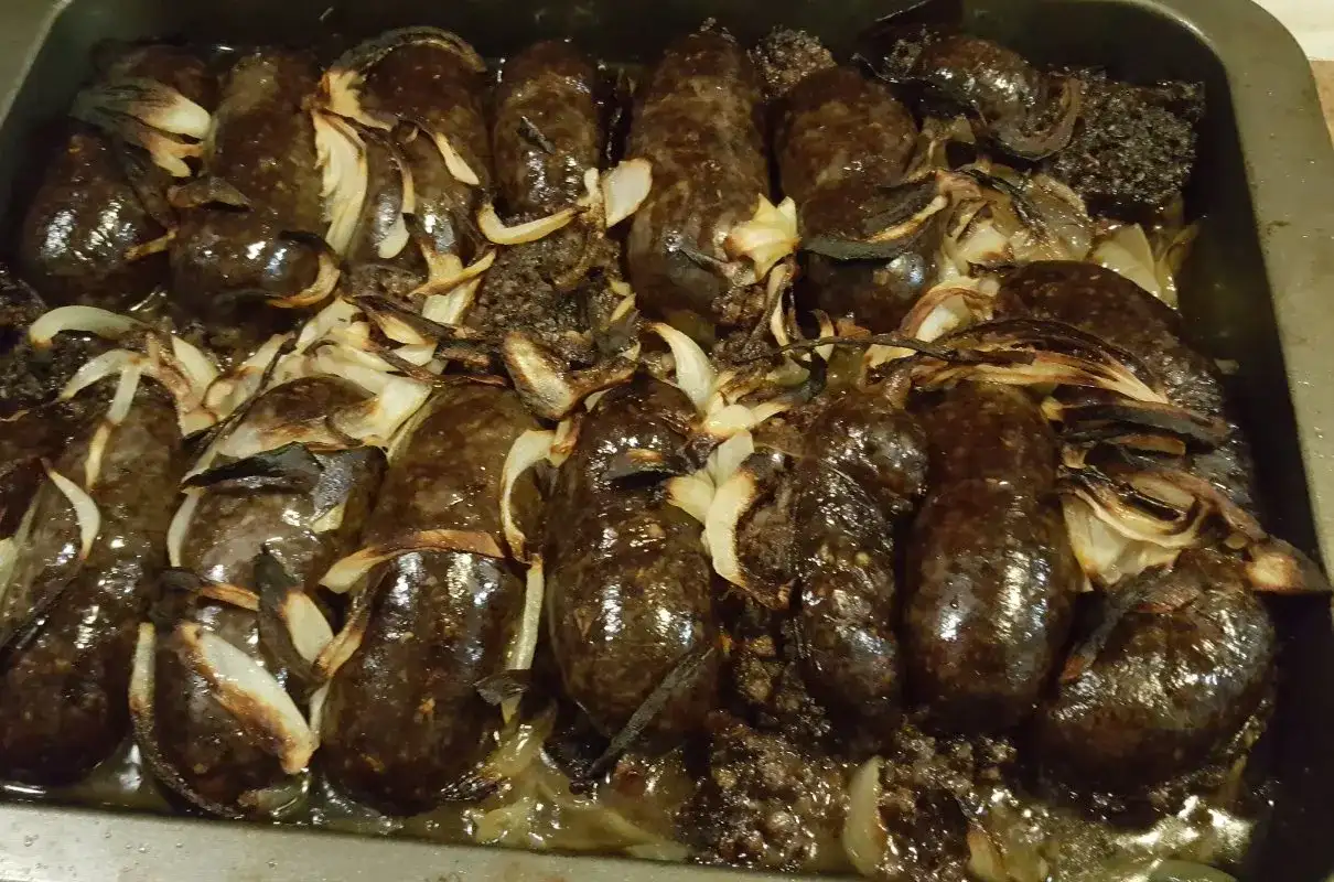 Kaszanka pieczona w piekarniku z cebulą, apetycznie przyrumieniona, gotowa do podania.