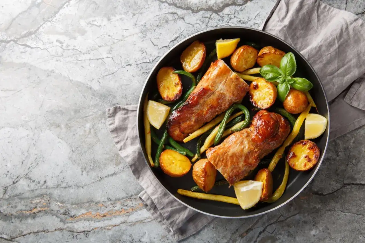 Dwie soczyste polędwiczki drobiowe w sosie, podane z pieczonymi ziemniaczkami, fasolką szparagową i cytryną.