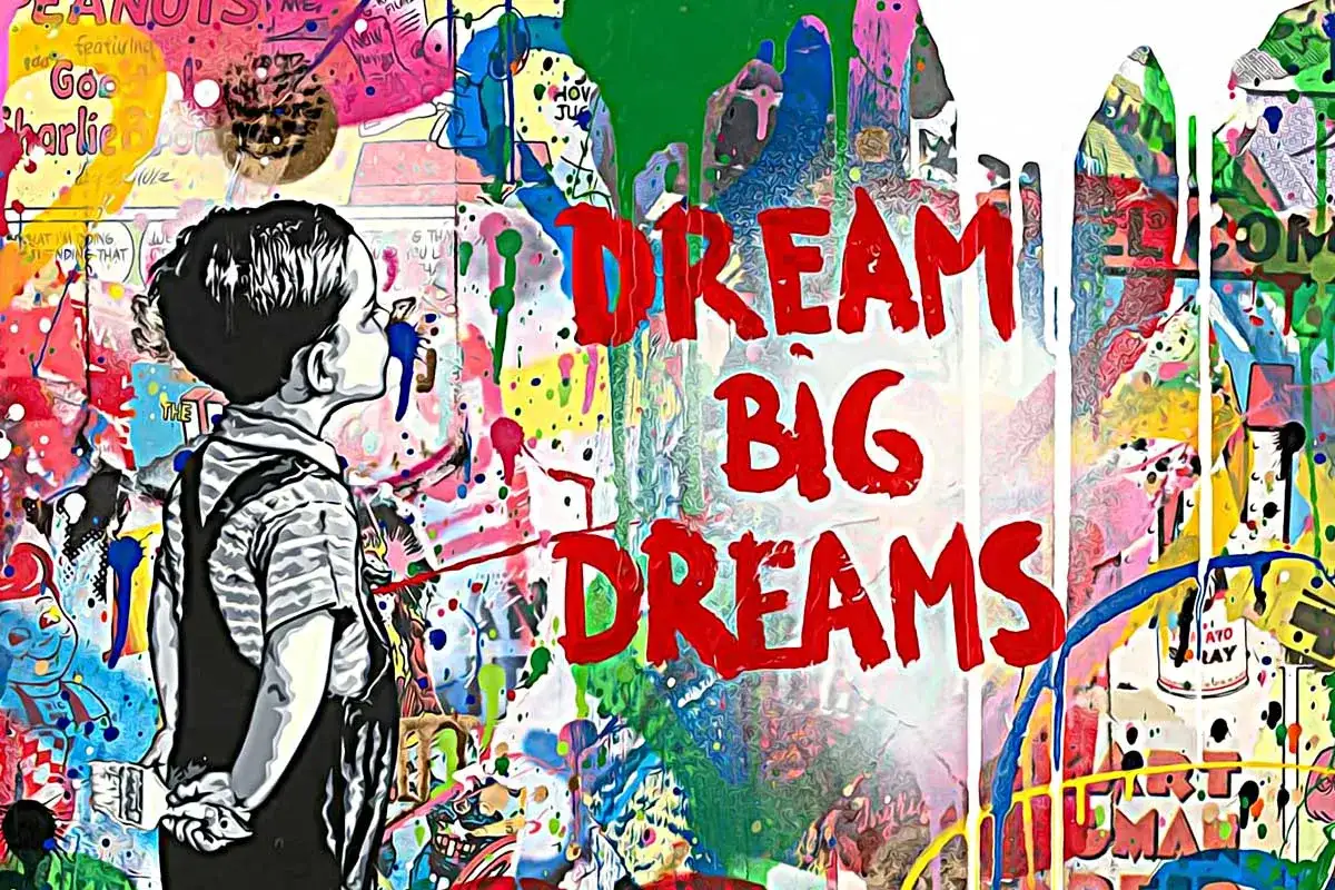 Graffiti mit Kind und den Worten "DREAM BIG DREAMS" vor bunter, spritziger Wand.