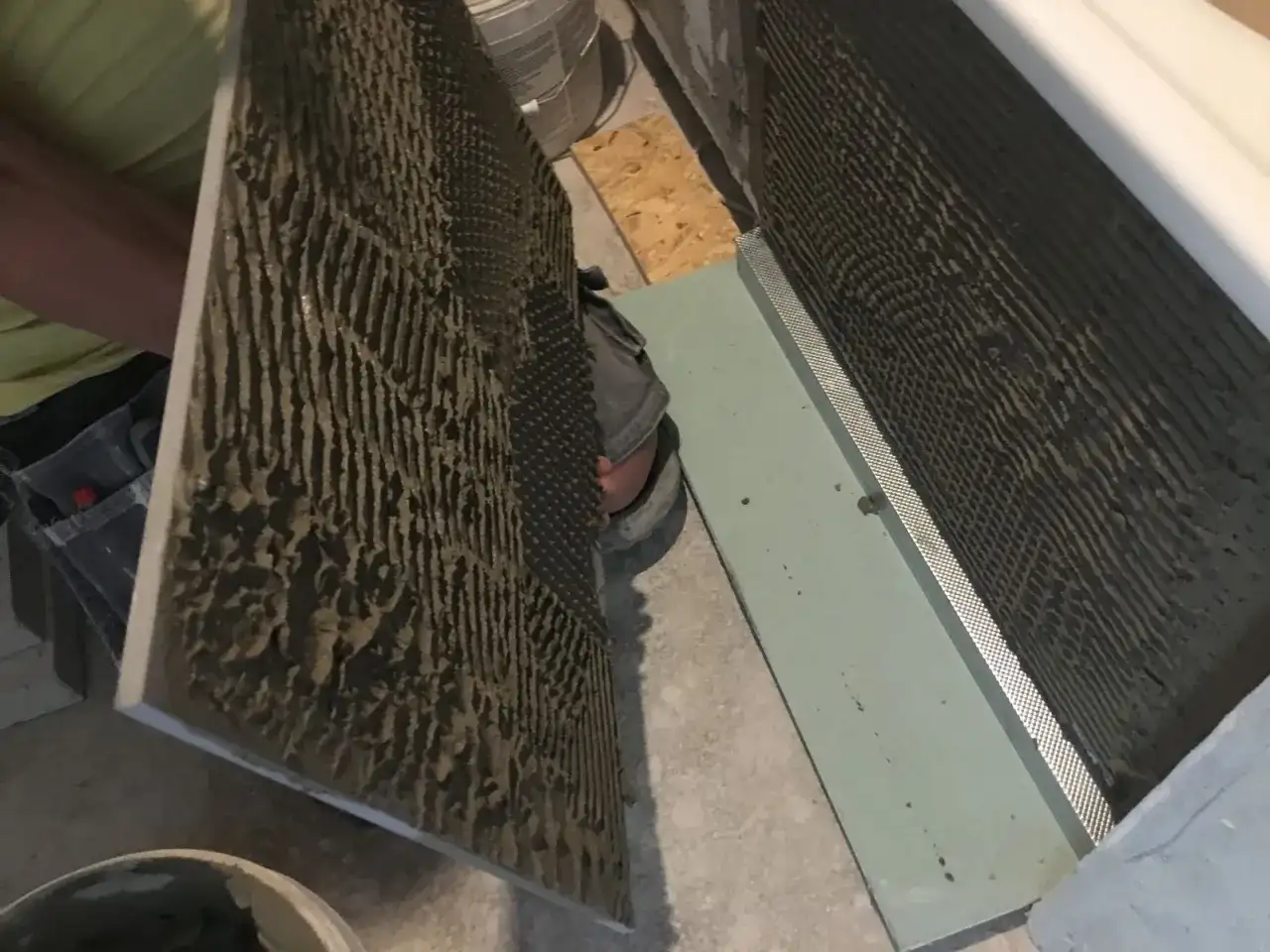 Płytkarz przygotowuje się do montażu, sprawdzając dopuszczalną grubość kleju pod płytki na dużej płycie.