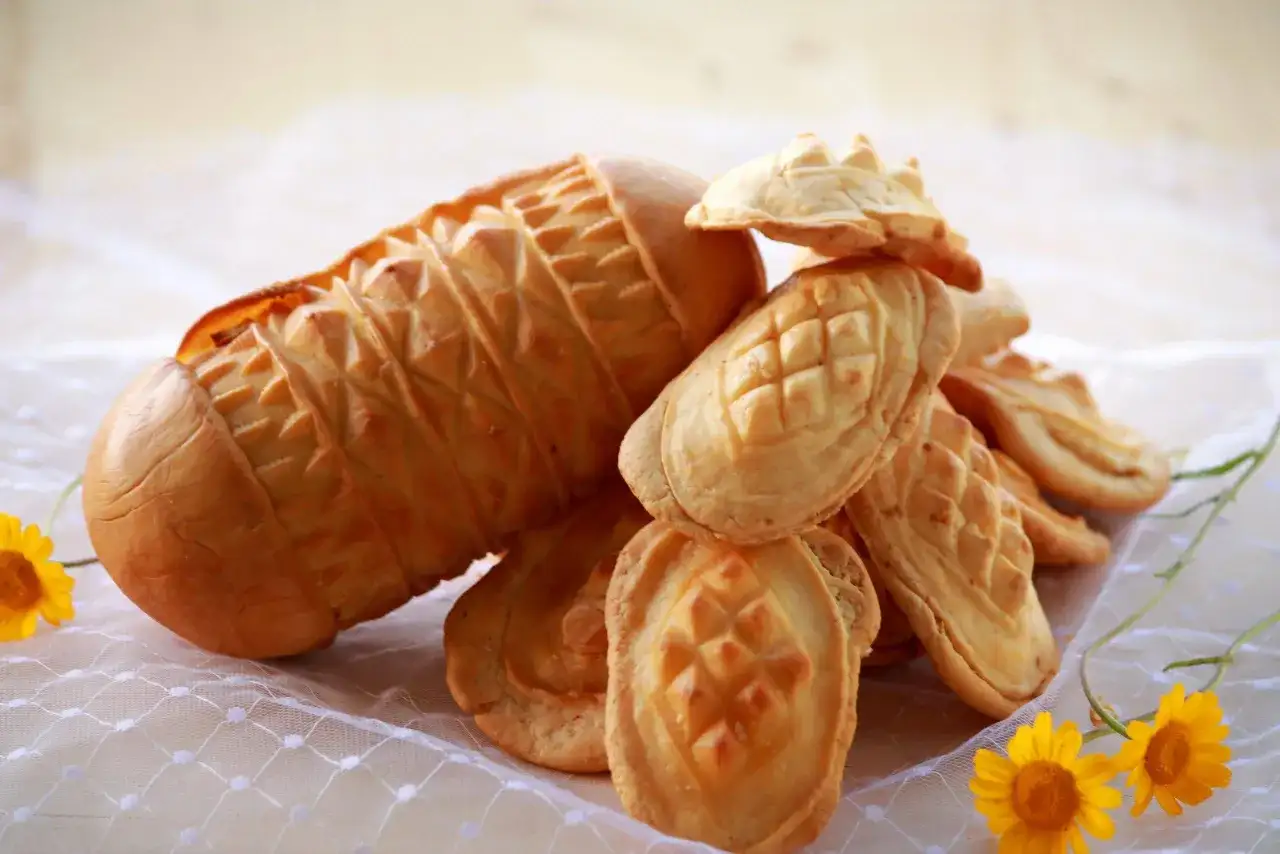 Stos oscypków i mniejszych serków góralskich z ozdobnymi wzorami, ozdobiony żółtymi kwiatami.