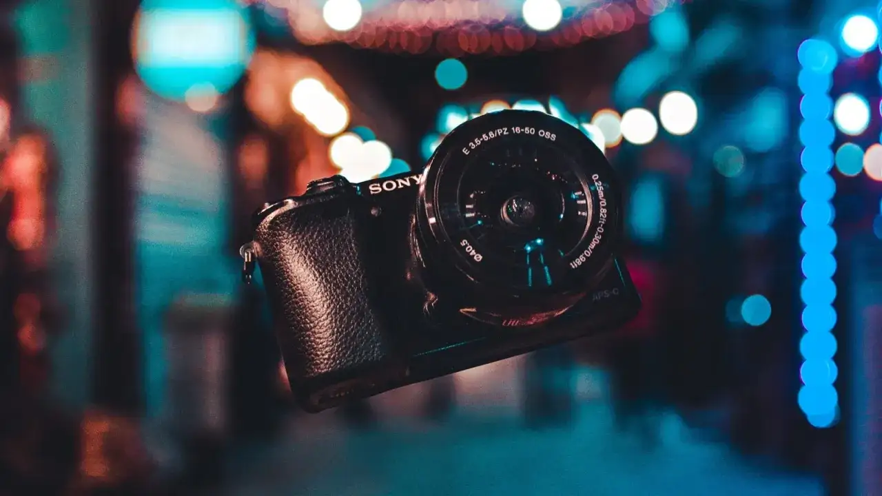 Aparat Sony z obiektywem na tle kolorowych świateł.