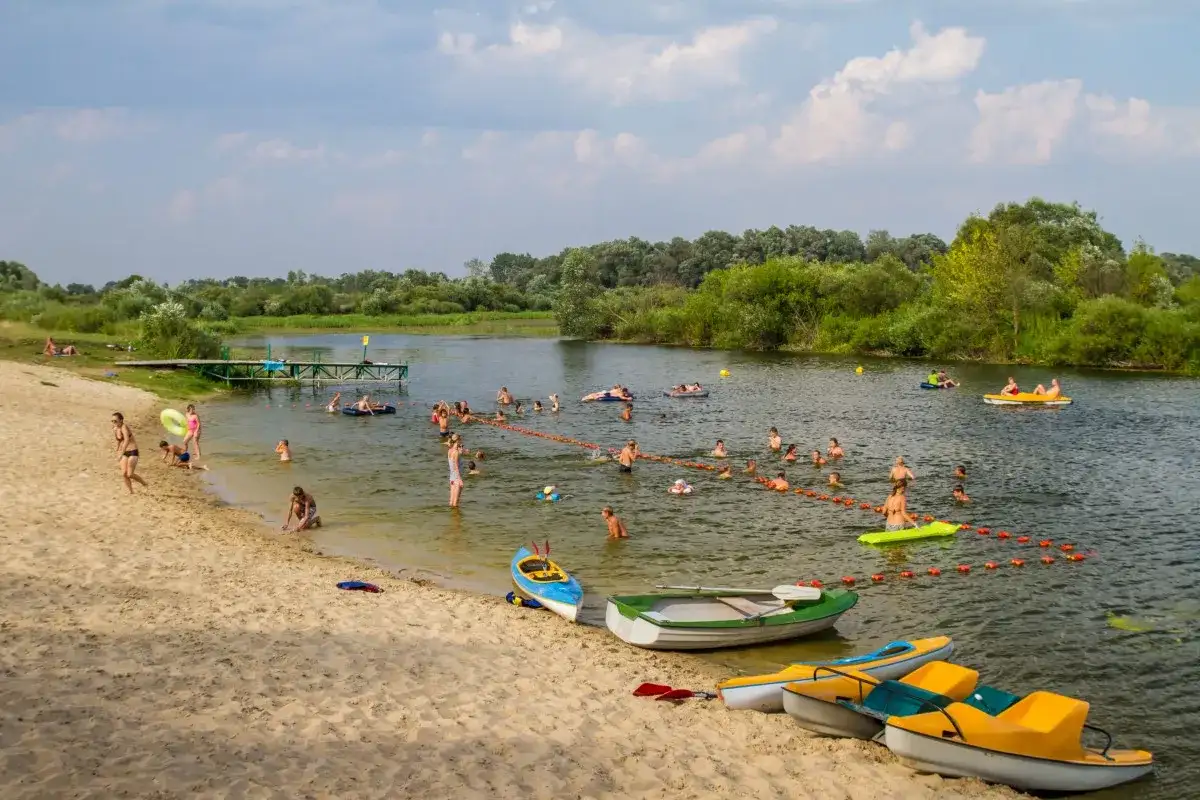 Wola Uhruska tętni życiem. Ludzie kąpią się, pływają na łódkach i relaksują na piaszczystej plaży.