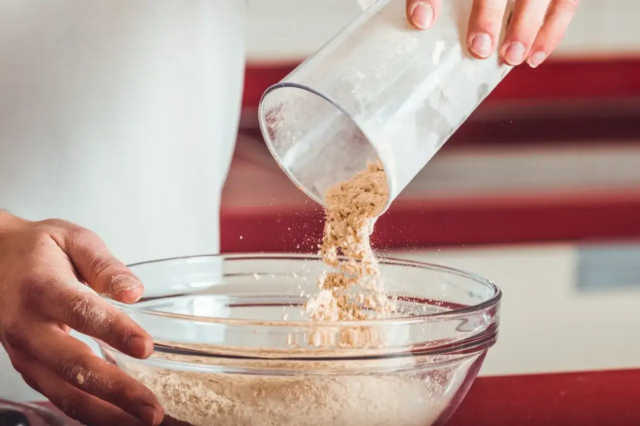 Wsypywanie mąki z pojemnika do szklanej miski.