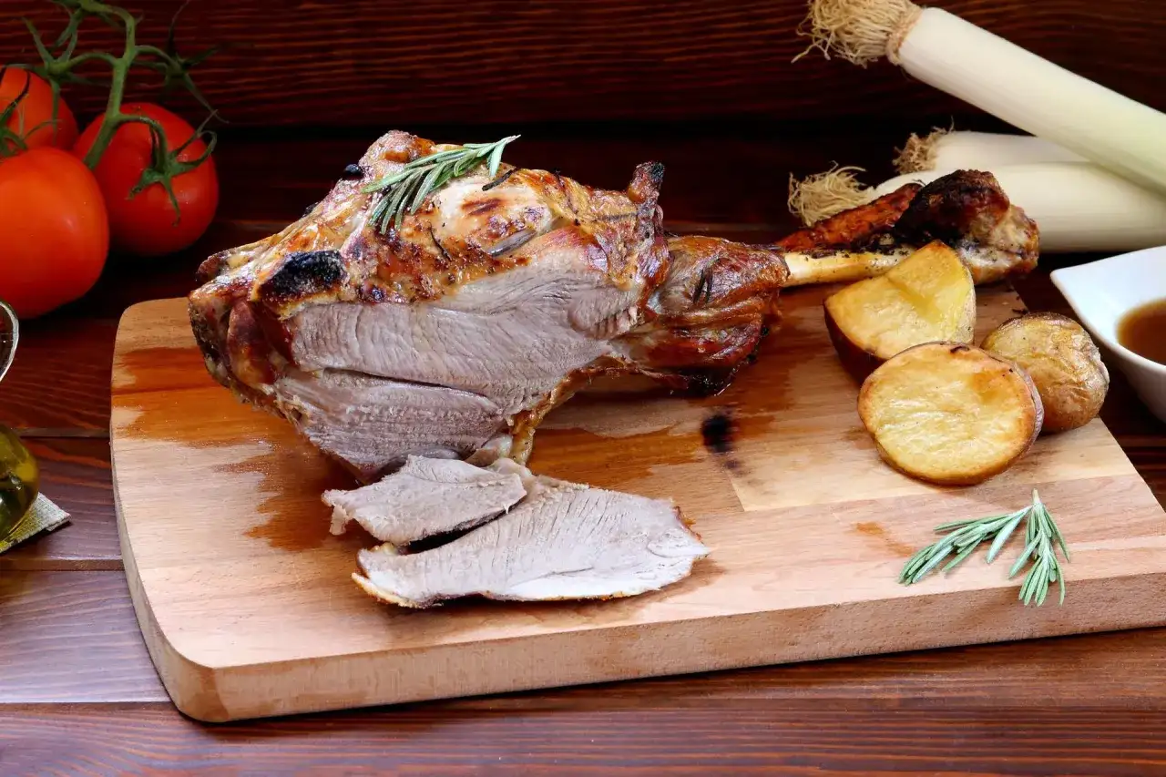 Pieczona jagnięcina z ziemniakami i rozmarynem na desce.