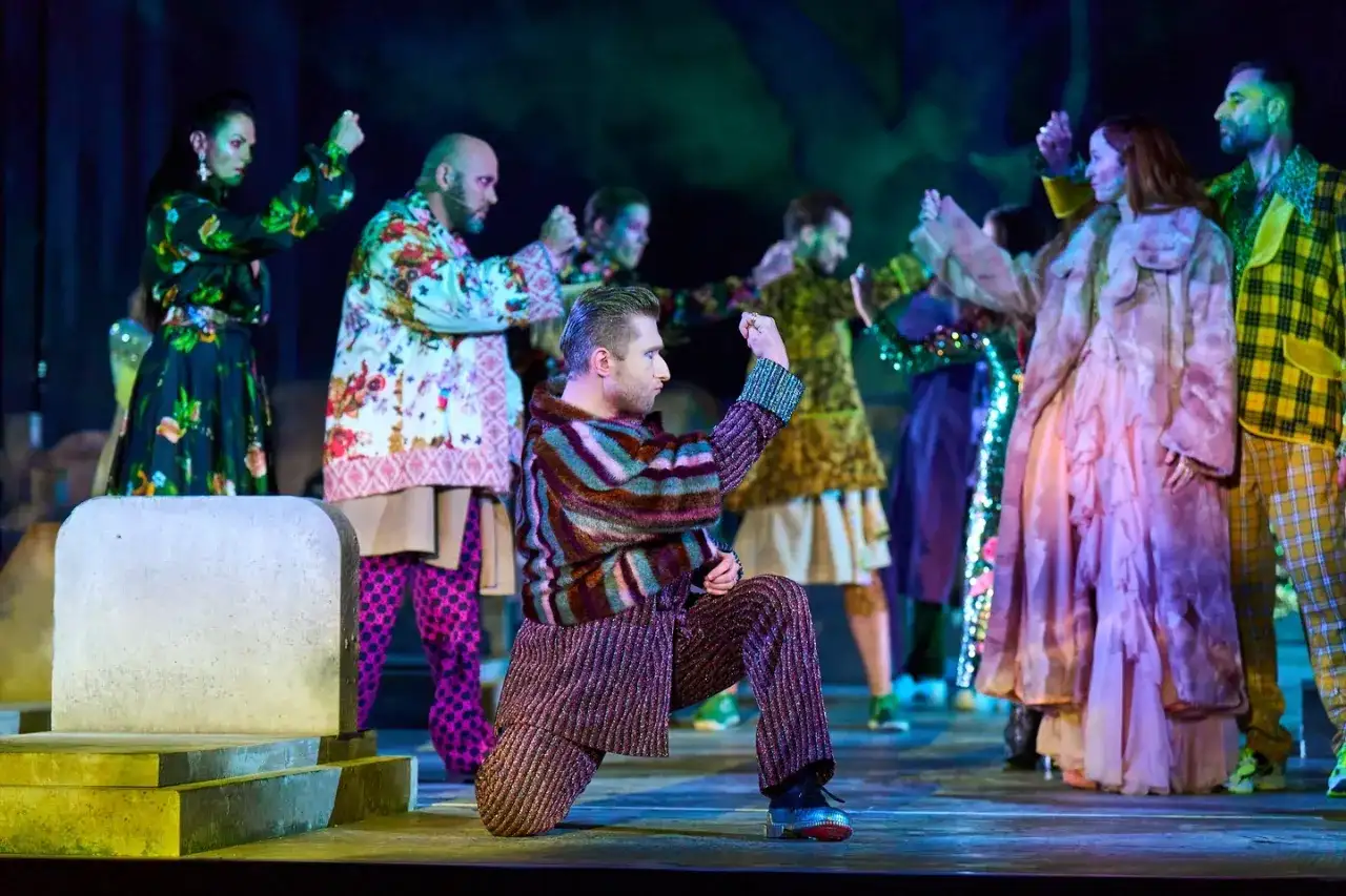 Scena z "Romeo i Julii" w angielskiej recenzji. Aktorzy w barwnych strojach tańczą na scenie.