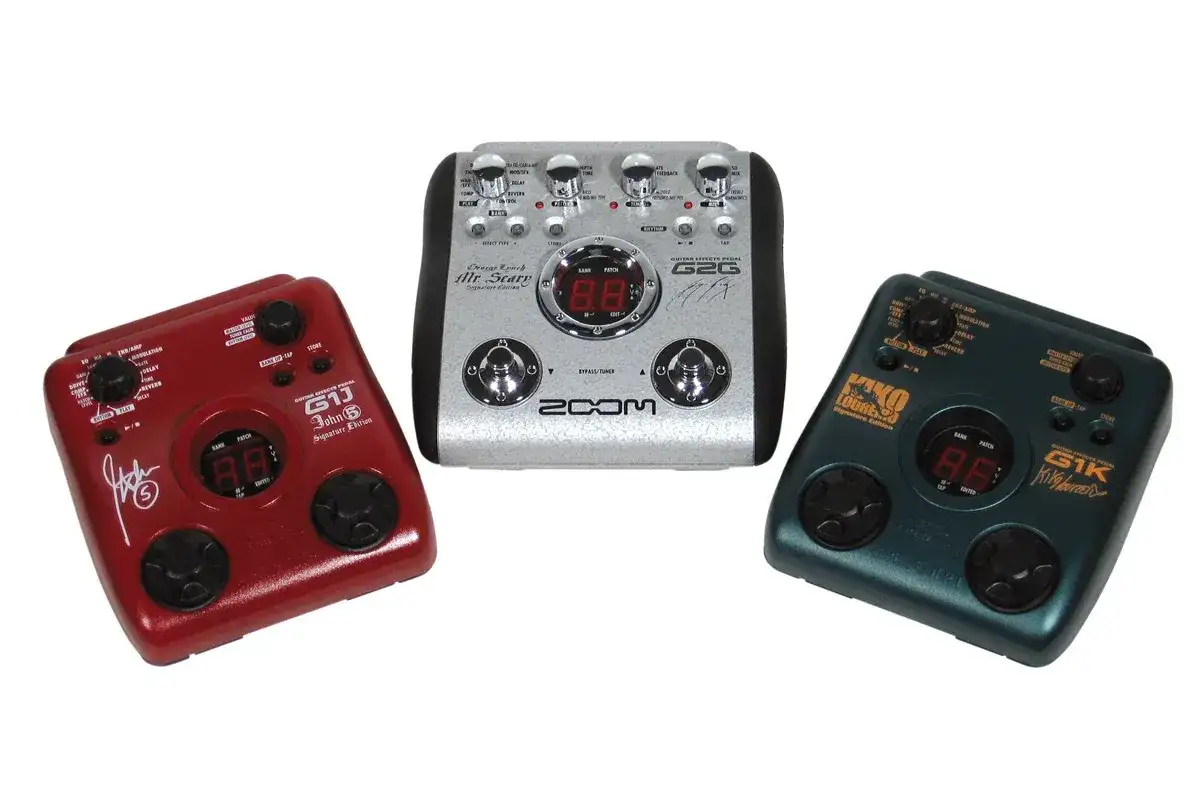 Trzy pedały gitarowe: czerwony, srebrny i zielony. Każdy to automat perkusyjny dla gitarzysty, z pokrętłami i wyświetlaczem.
