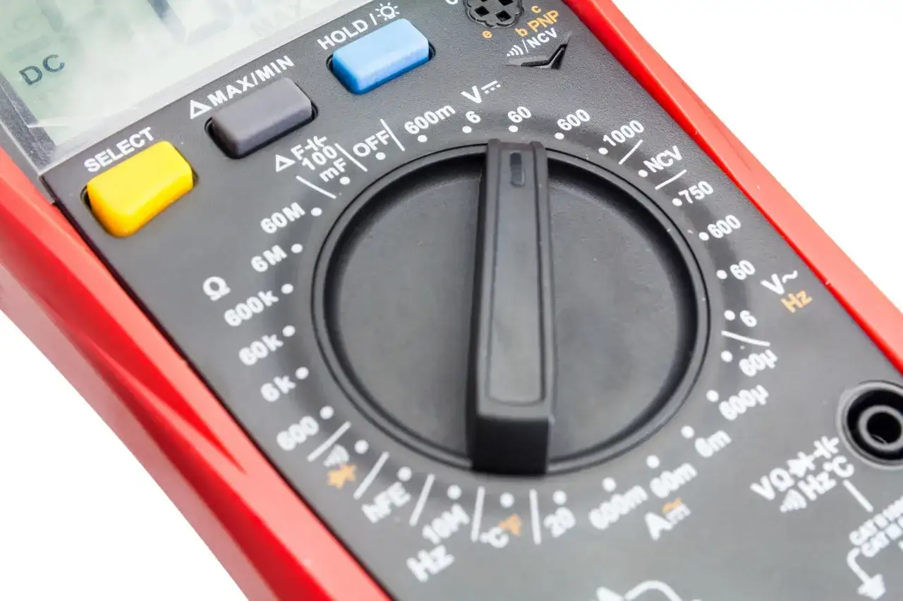 Zbliżenie na panel cyfrowego multimetru z pokrętłem wyboru funkcji i przyciskami.