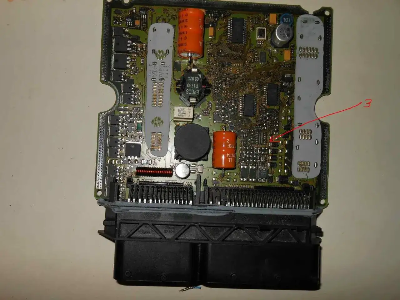 Czerwona strzałka wskazuje miejsce na płycie głównej, gdzie może wystąpić zwarcie do plusa, co oznacza uszkodzenie układu.