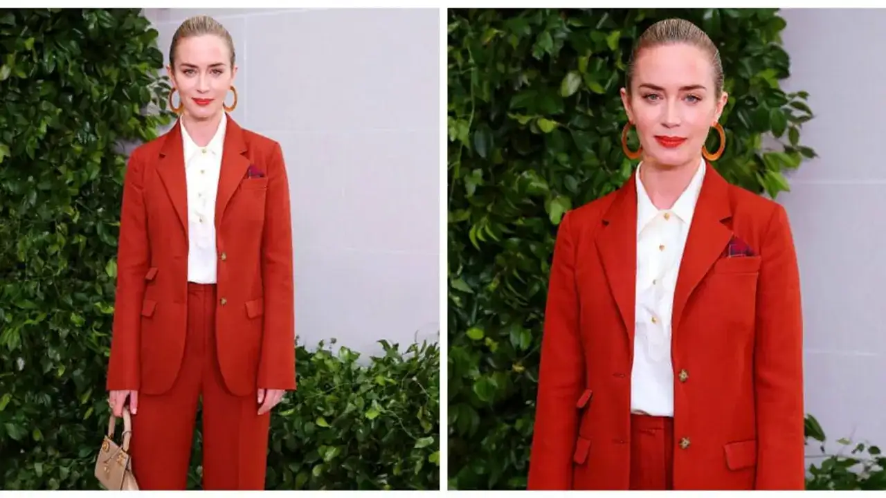 Elegancki komplet czerwony damski Emily Blunt. Aktorka prezentuje się stylowo w garniturze i białej koszuli, z torebką i okrągłymi kolczykami.
