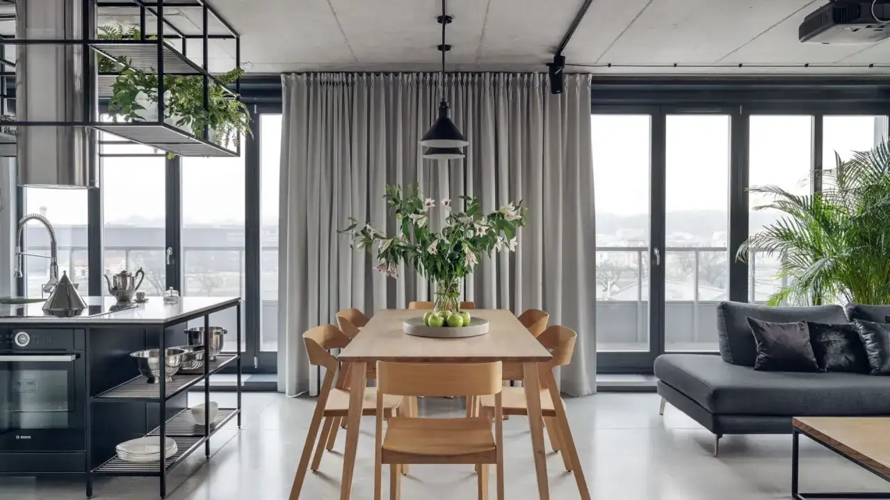 Nowoczesna lampa do jadalni nad drewniany stół z bukietem kwiatów i zielonymi jabłkami.