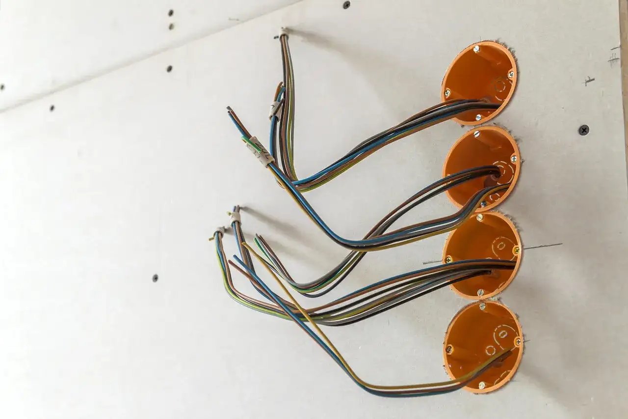 Instalacja elektryczna w trakcie prac. Widoczne puszki instalacyjne i przewody, czekające na maskownicę na ścianę.