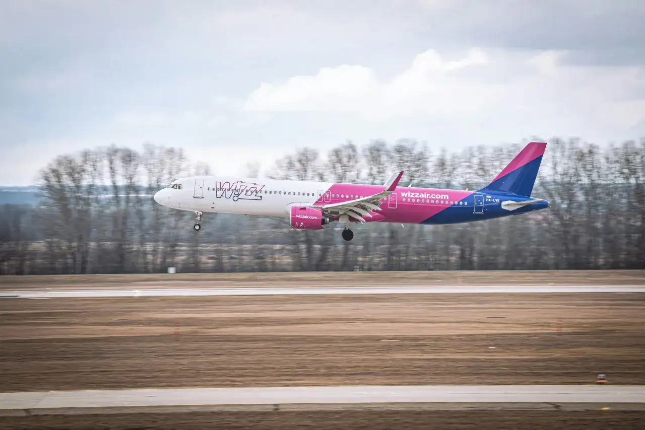 Samolot Wizz Air z wysuniętym podwoziem ląduje na pasie startowym.
