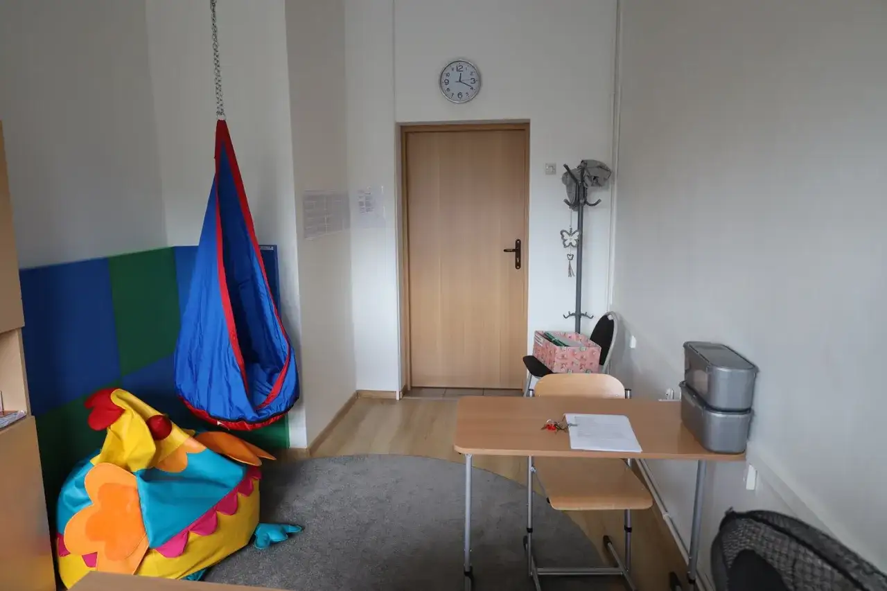 Przytulny gabinet pedagoga szkolnego z kolorowym workiem sako w kształcie ptaka, huśtawką i biurkiem.