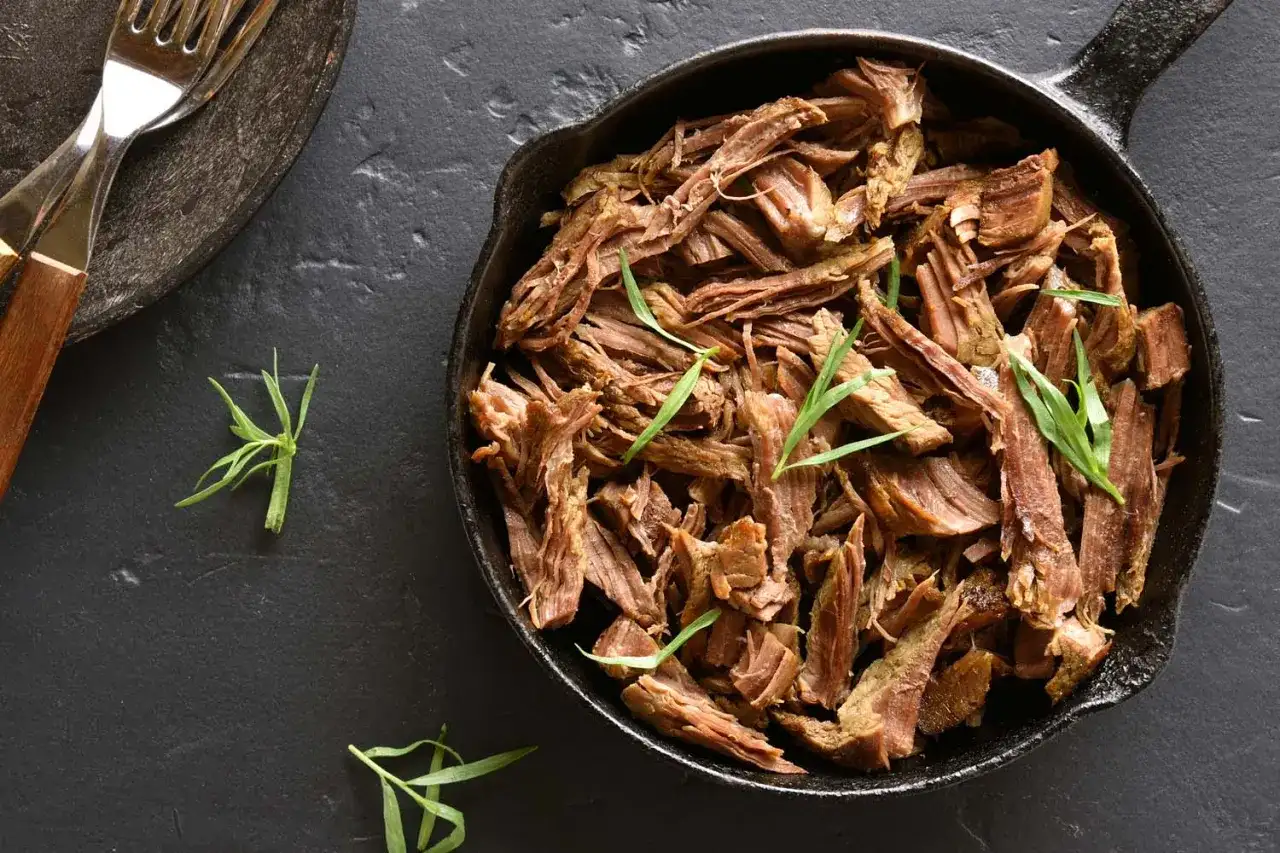 Szarpana wieprzowina w żeliwnej patelni, gotowa do podania. Idealna do kanapek i dań głównych. Ten przepis na szarpaną wieprzowinę jest prosty i pyszny.