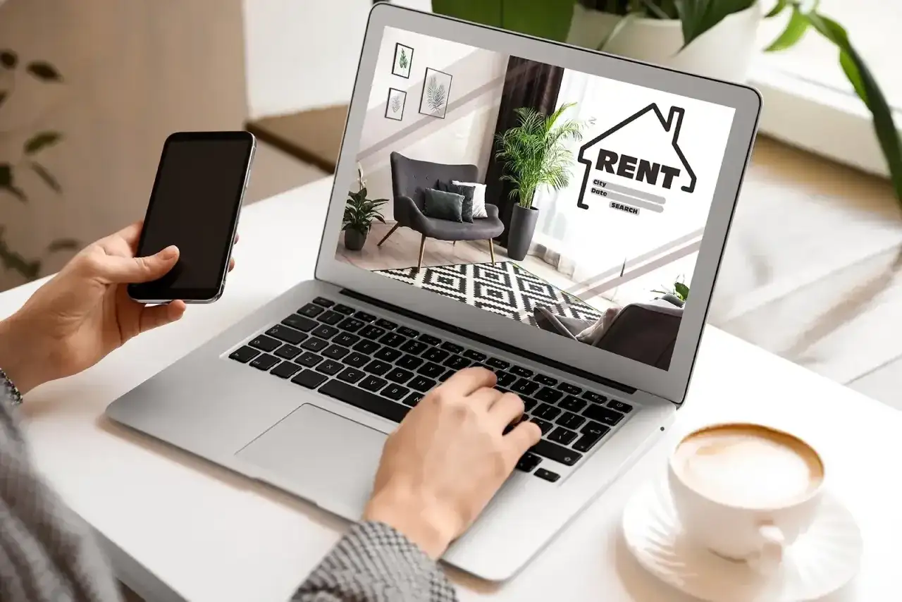 Szukasz mieszkania? Na co zwrócić uwagę przy wynajmie? Laptop pokazuje ofertę, a telefon jest pod ręką.