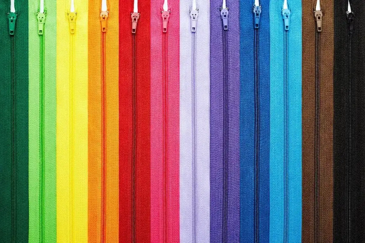 Kolorowe zamki błyskawiczne ułożone pionowo, idealne do nauki jak wszyć zamek kryty.