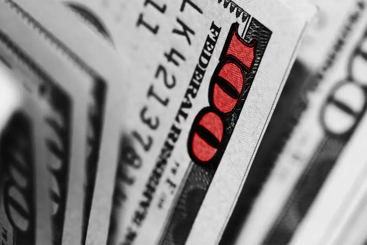 Zbliżenie na banknot 100 dolarów z czerwonym oznaczeniem liczby 100.