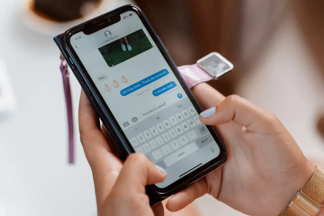 Dłonie trzymające smartfon, na ekranie rozmowa. Gdzie są gry na Messengerze? Tutaj piszemy wiadomości, a nie gramy.