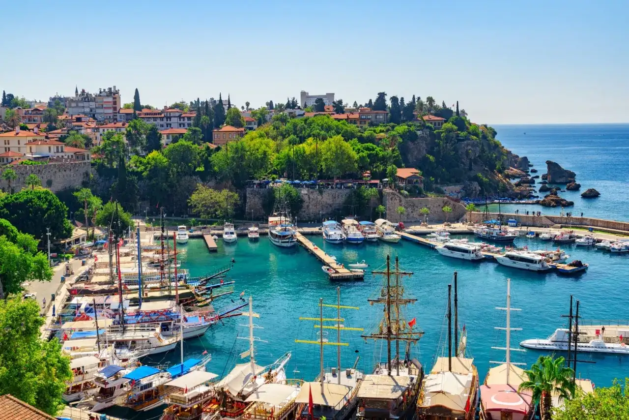 Malowniczy port z licznymi łodziami i jachtami, na wzgórzu widać zabudowania. Czy wakacje w Turcji są bezpieczne? Tak, ten widok to dowód na spokojny wypoczynek.