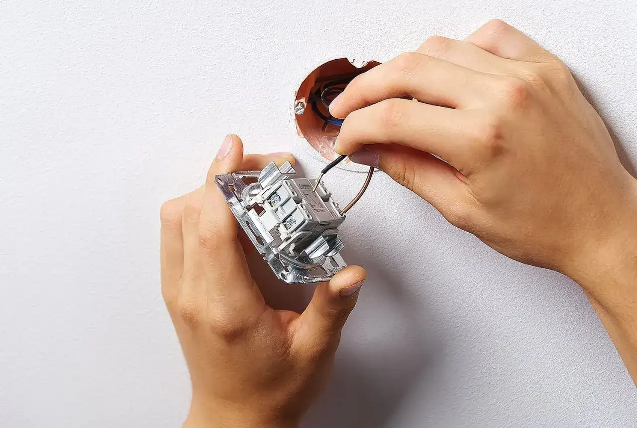 Instalacja podwójnego włącznika światła 2 kable. Dłonie montują mechanizm w puszce, podłączając przewody.