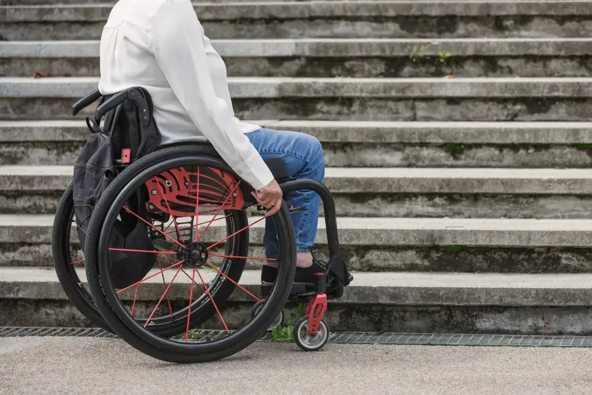 Osoba na wózku inwalidzkim przed schodami. Umiarkowany stopień niepełnosprawności a emerytura – ważna kwestia dla wielu osób.