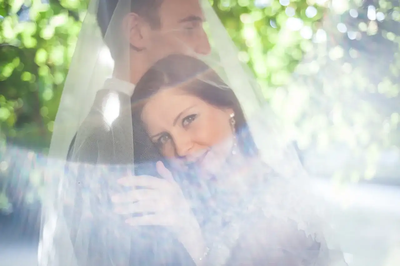Para młoda pod welonem, z welonu przebija światło, tworząc efekt flary.