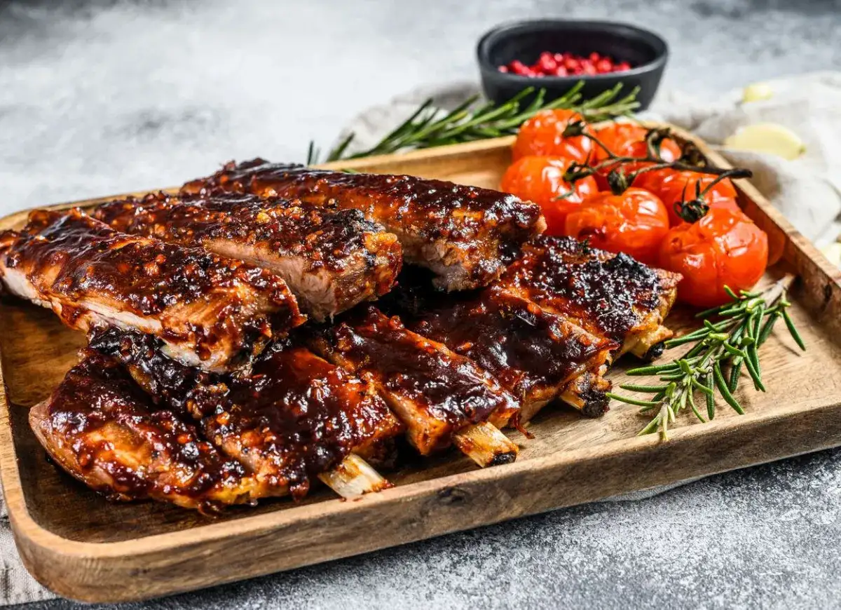 Soczyste żeberka w sosie barbecue, podane z pieczonymi pomidorkami i rozmarynem. Idealne danie, gdy zastanawiasz się, co zrobić z ugotowanych żeberek.