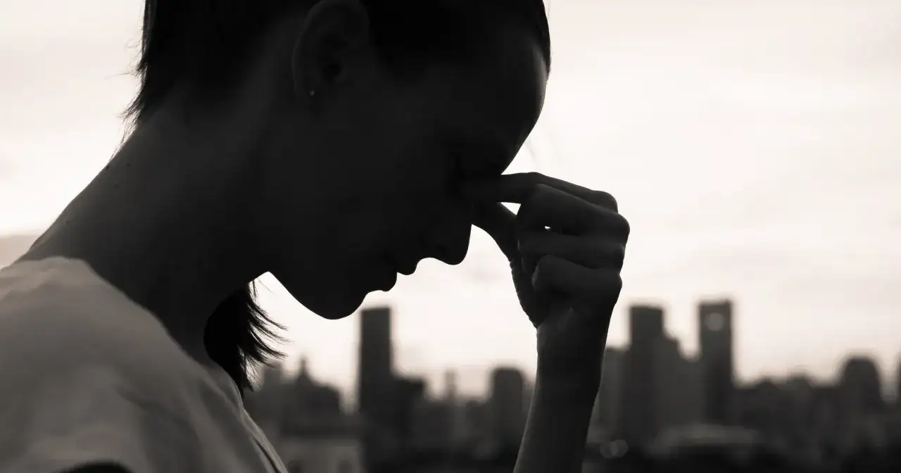 Sylwetka kobiety z dłonią na czole, zamyślona. Czy to objawy depresji? Test 9 pytań może pomóc.