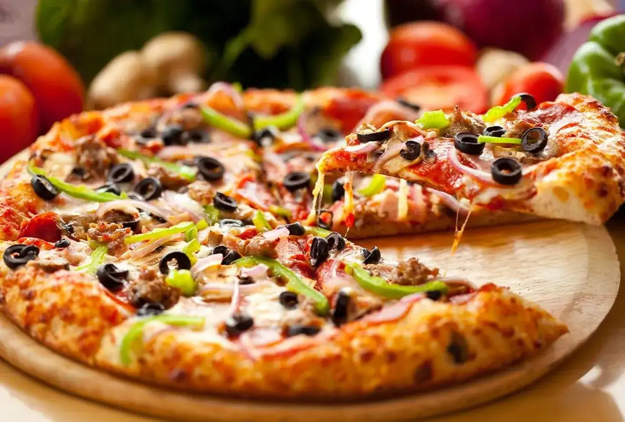 Gorąca pizza z ciągnącym serem, oliwkami i papryką na desce.