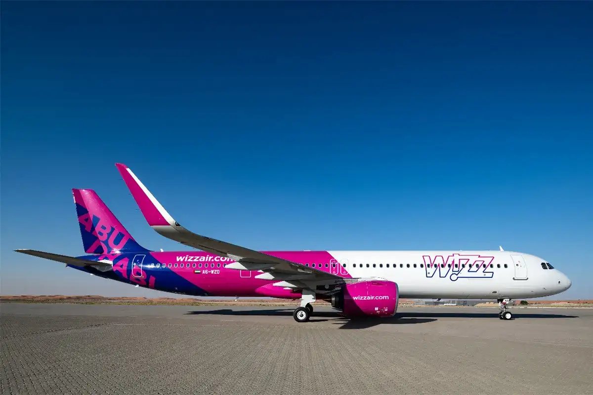 Samolot Wizz Air z różowo-niebieskim malowaniem na tle błękitnego nieba.