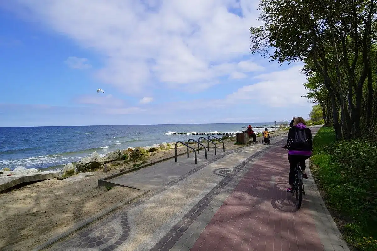 Rowerzystka na ścieżce nad morzem. Zastanawiasz się, ile kilometrów jest z Koszalina do Kołobrzegu? Ta malownicza trasa zachęca do aktywnego wypoczynku.