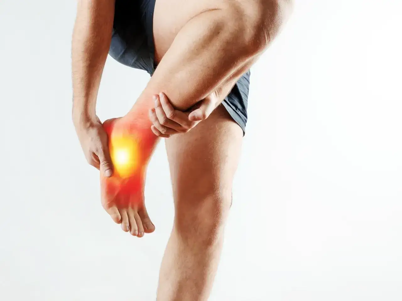 Mężczyzna trzymający się za bolącą stopę z zaznaczonym bólem.