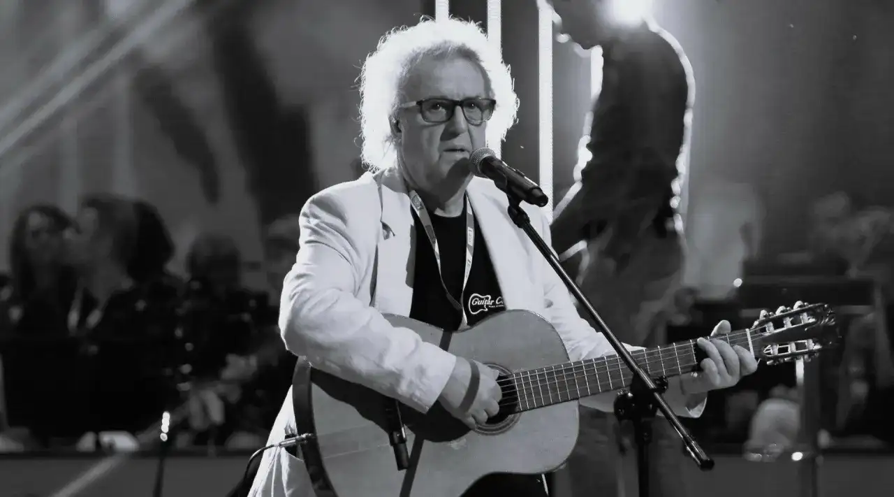 Zegarmistrz światła purpurowy chwyty na gitarze, w białej marynarce, śpiewa do mikrofonu.