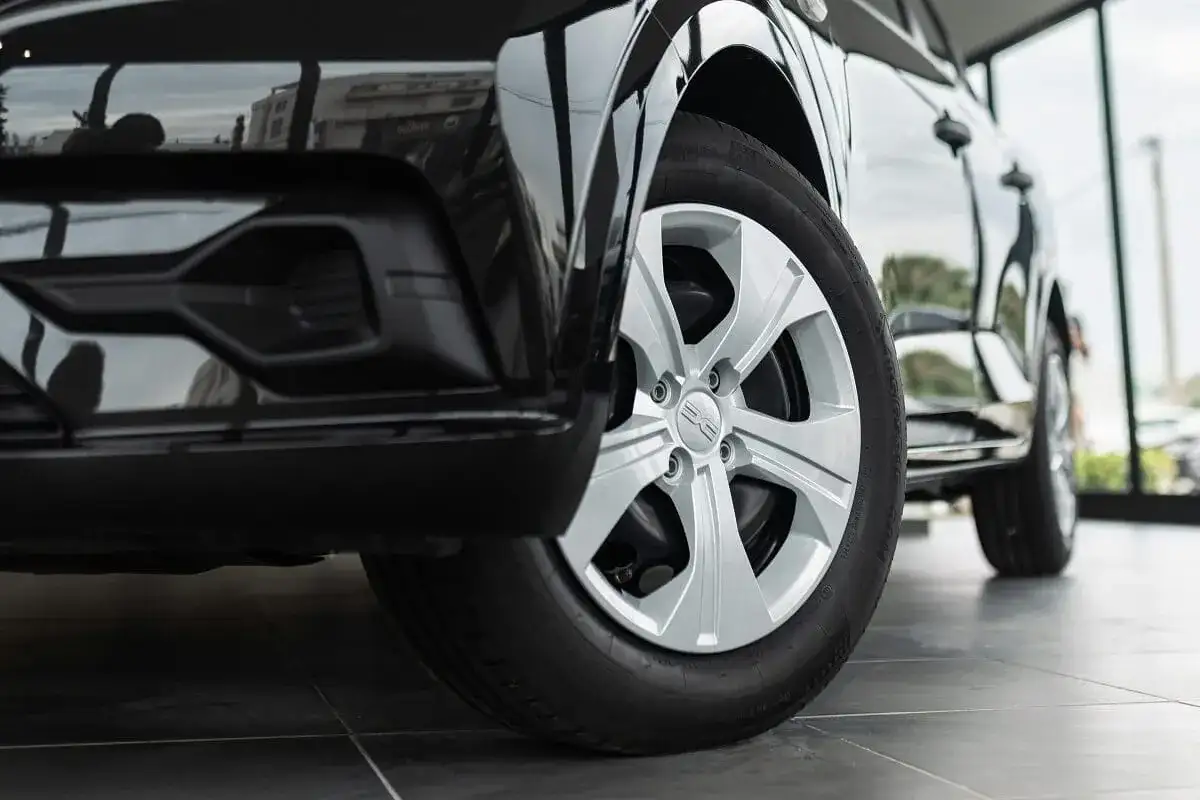 Zbliżenie na przednie koło czarnego Dacia Duster z oponami letnimi. Felga aluminiowa z logo marki.