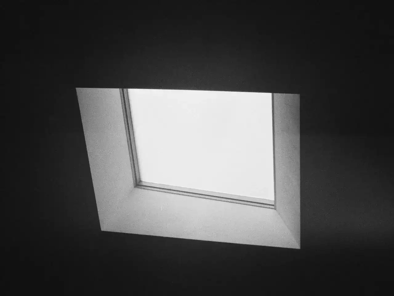 Szare, uchylne okno w ciemnej ścianie.